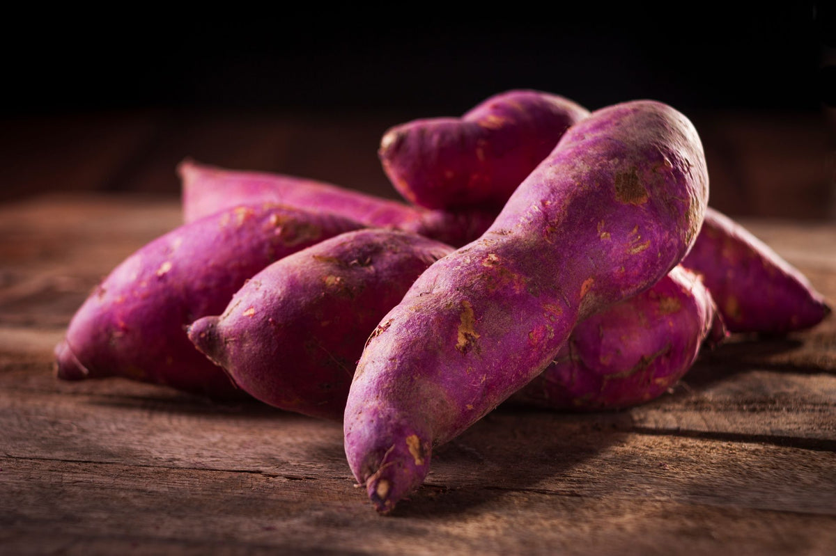 Ube violet en gros plan sur une surface en bois clair, tubercule brut aux antioxydants naturels
