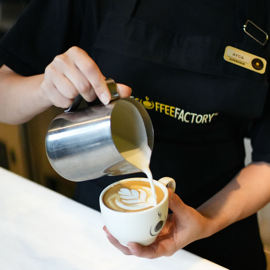 Barista versant du lait pour créer un latte art dans un café, préparation de boisson tendance