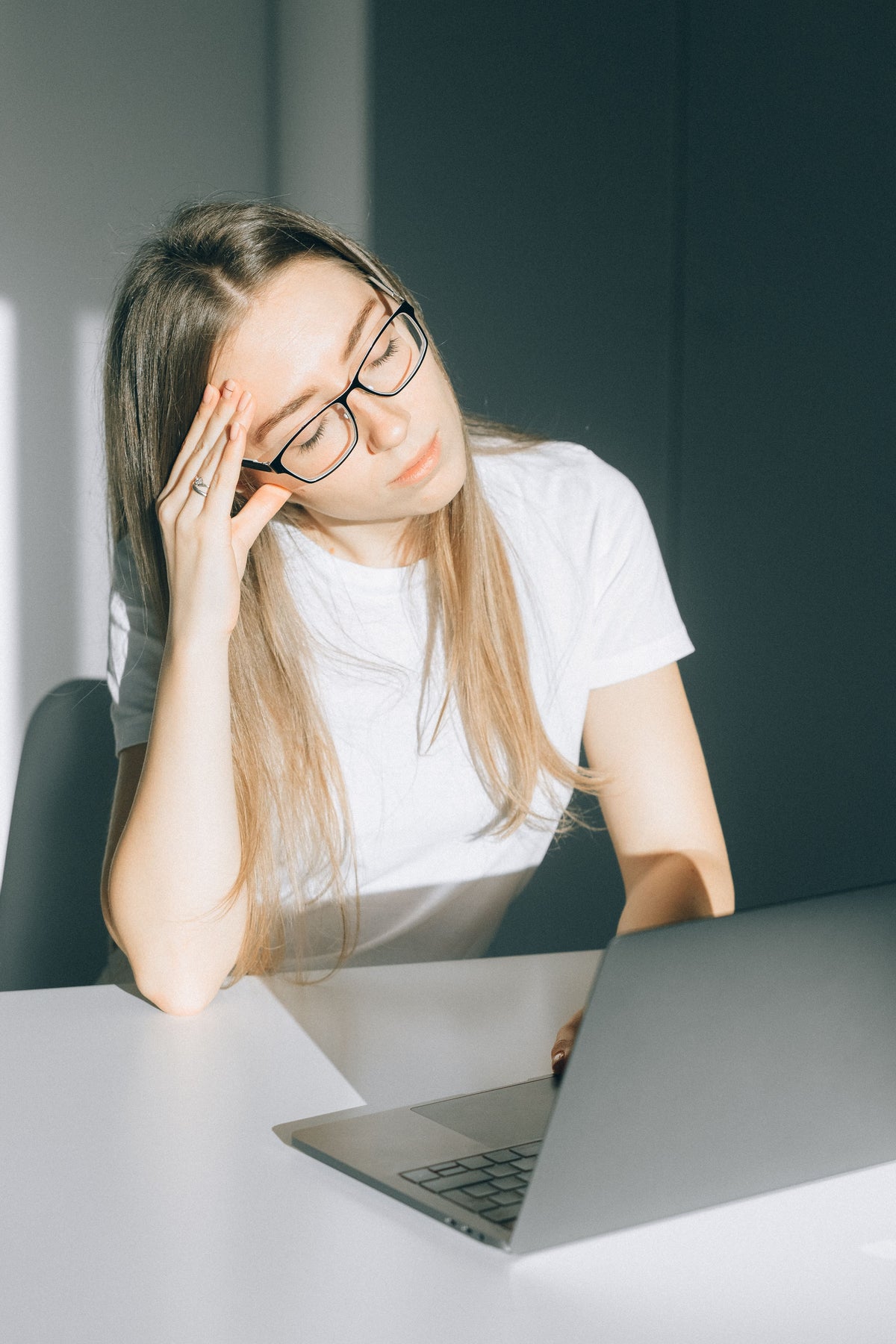 Jeune femme fatiguée travaillant à son bureau malgré une nuit de sommeil correcte, illustration de la fatigue liée à l'alimentation