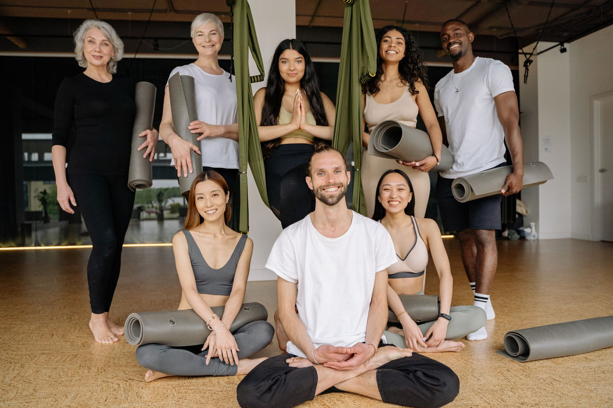 Groupe de personnes souriantes pratiquant le yoga ensemble dans un studio lumineux