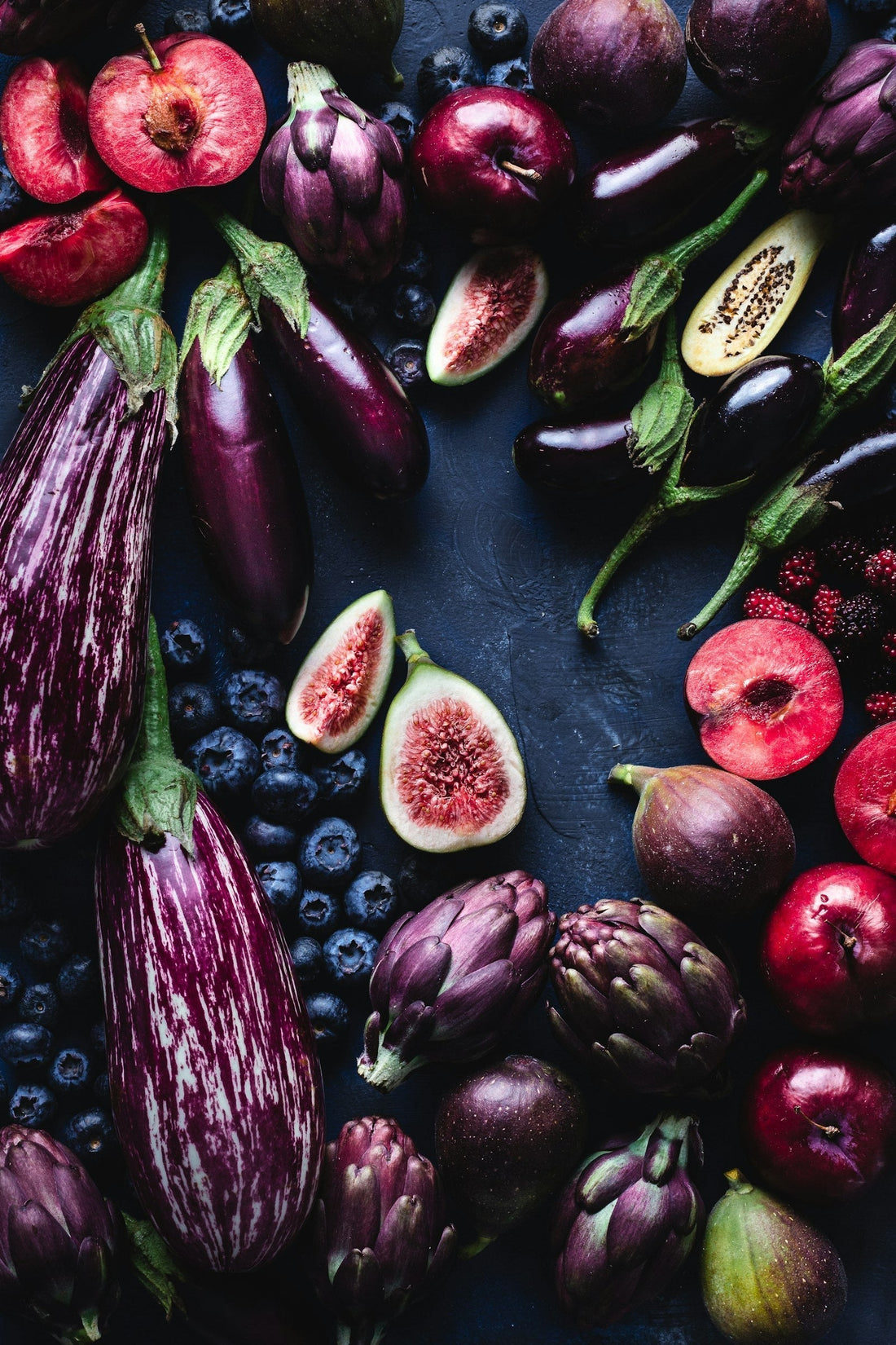 Assortiment de fruits et légumes violets riches en anthocyanines : aubergines, figues, mûres et prunes