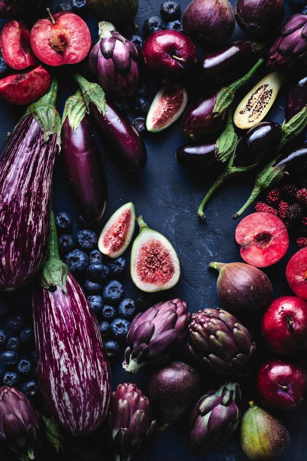 Assortiment de fruits et légumes violets riches en anthocyanines : aubergines, figues, mûres et prunes