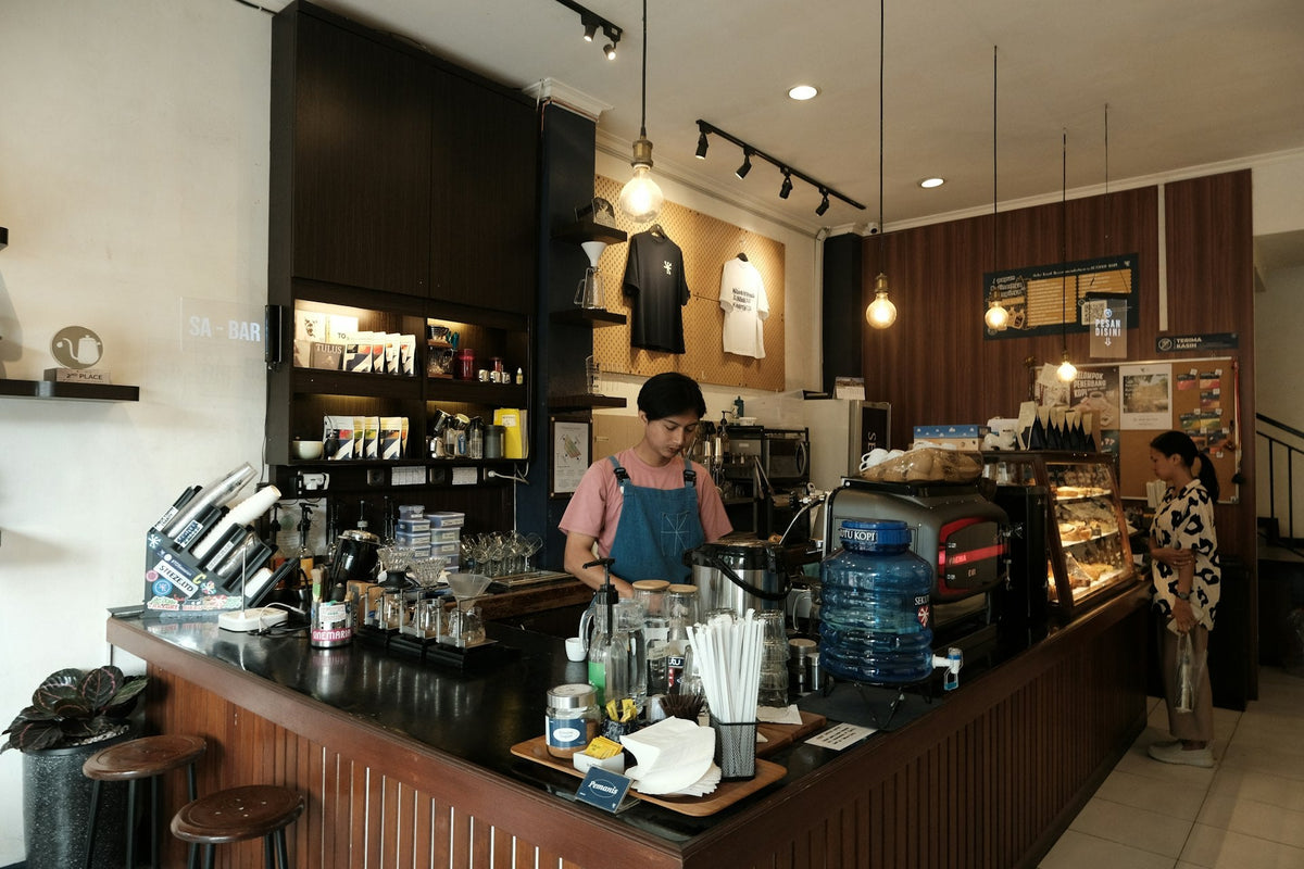 Barista préparant une boisson derrière le comptoir d'un café, ambiance accueillante et professionnelle