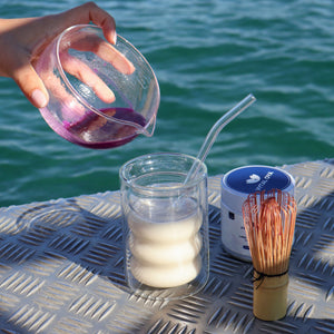 Préparation d'un ube latte Vytal Oya avec poudre d'ube et lait versé dans un verre.