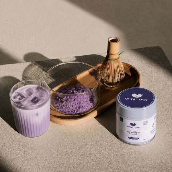 Ube latte violet avec poudre d'ube, fouet en bambou et pot Vytal Oya Original sur un plateau minimaliste.